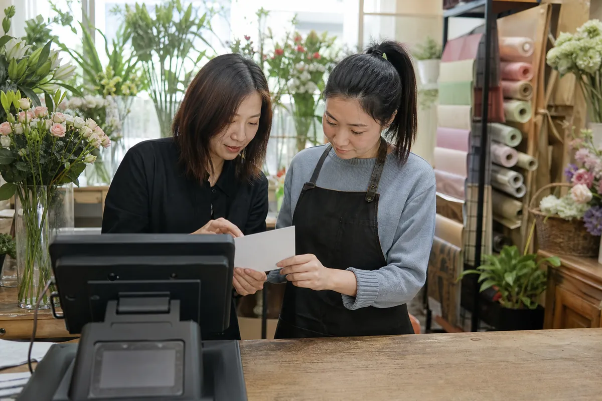 中国花店两名员工在通用收银终端旁查看空白卡片
